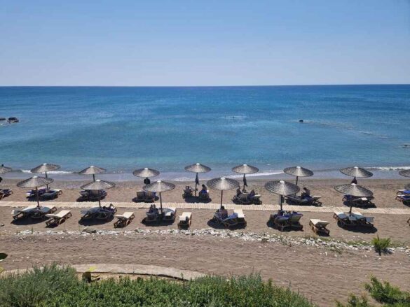 Relaxing on the pristine beach at Atrium Prestige, Rhodes, with crystal-clear water and small pebbles.