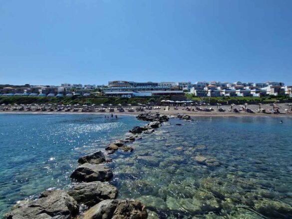 Relaxing on the pristine beach at Atrium Prestige, Rhodes, with crystal-clear water and small pebbles.