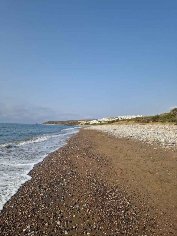 Relaxing on the pristine beach at Atrium Prestige, Rhodes, with crystal-clear water and small pebbles.