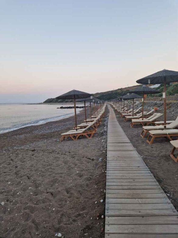 Relaxing on the pristine beach at Atrium Prestige, Rhodes, with crystal-clear water and small pebbles.