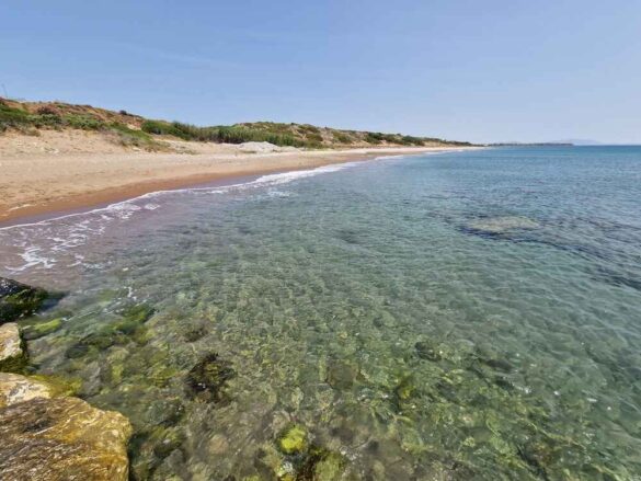 Relaxing on the pristine beach at Atrium Prestige, Rhodes, with crystal-clear water and small pebbles.